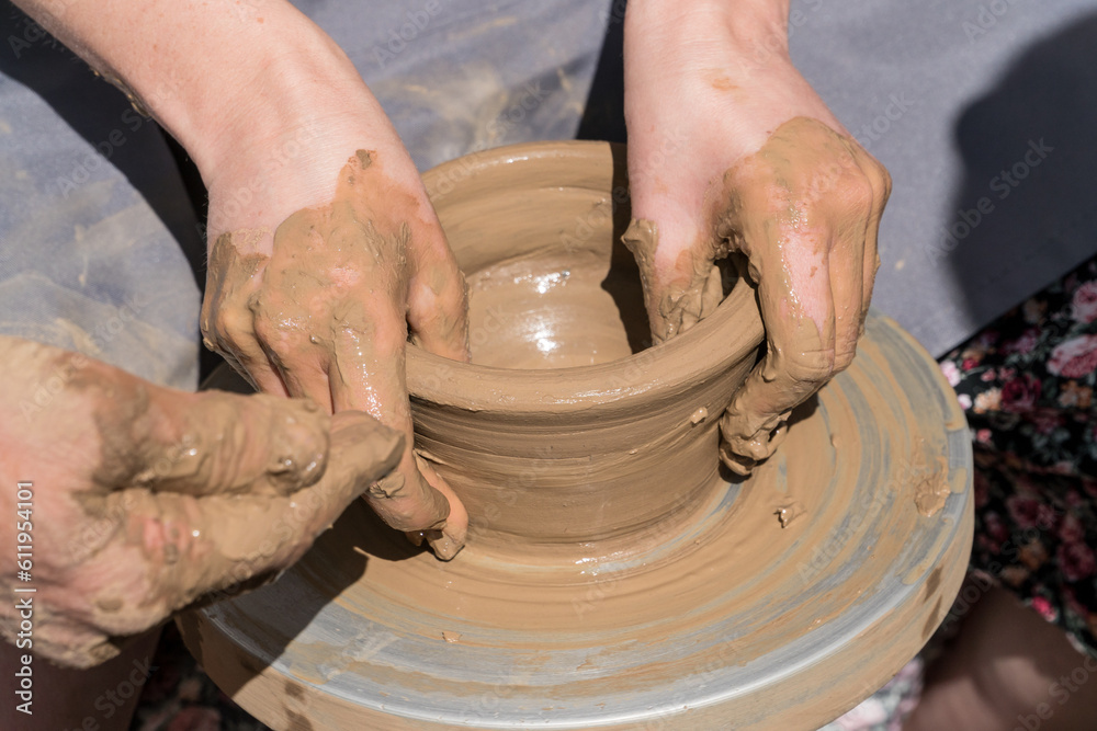 Close up shot of hands making clay bowl during pottery lessons.