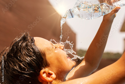 Heat wave. Young man throwing water from the bottle over his head due to heat wave in summer