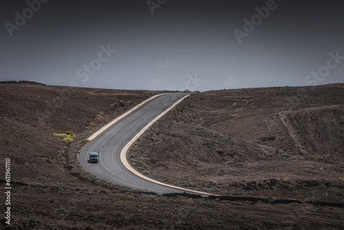 Single van driving on the empty road through the black sand desert in Lanzarote