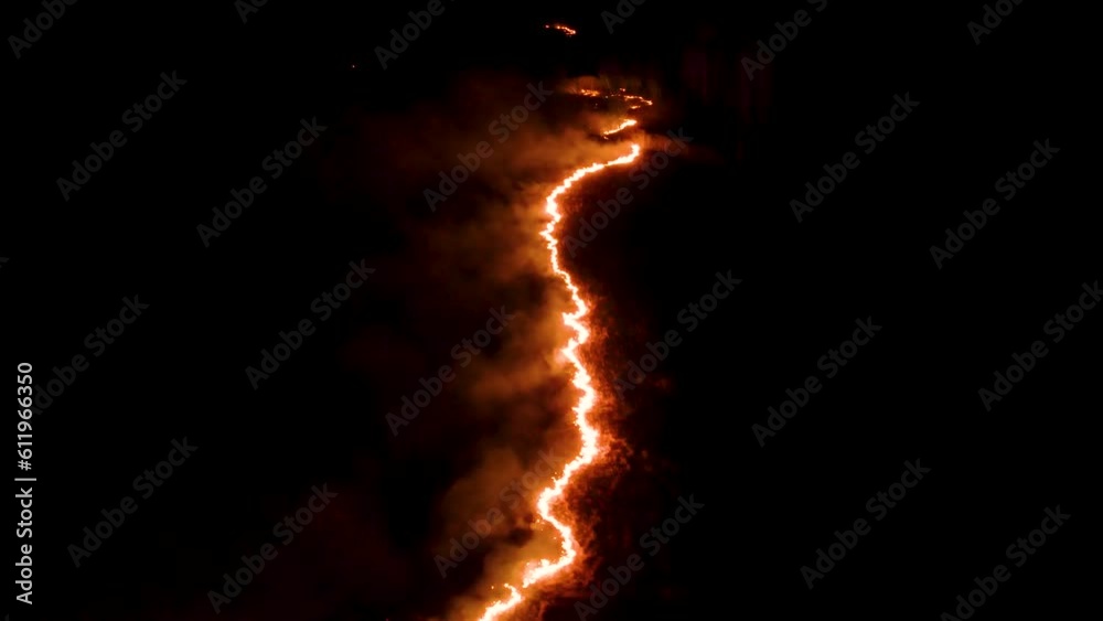 Night fire in the forest with fire and smoke.Epic aerial video of a smoking wild flame.A blazing,glowing fire at night.Forest fires.Dry grass is burning. climate change,ecology.Line fire in the dark.