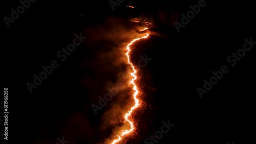 Night fire in the forest with fire and smoke.Epic aerial video of a smoking wild flame.A blazing,glowing fire at night.Forest fires.Dry grass is burning. climate change,ecology.Line fire in the dark.