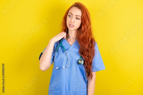young red-haired doctor woman over yellow studio background stressed, anxious, tired and frustrated, pulling shirt neck, looking frustrated with problem