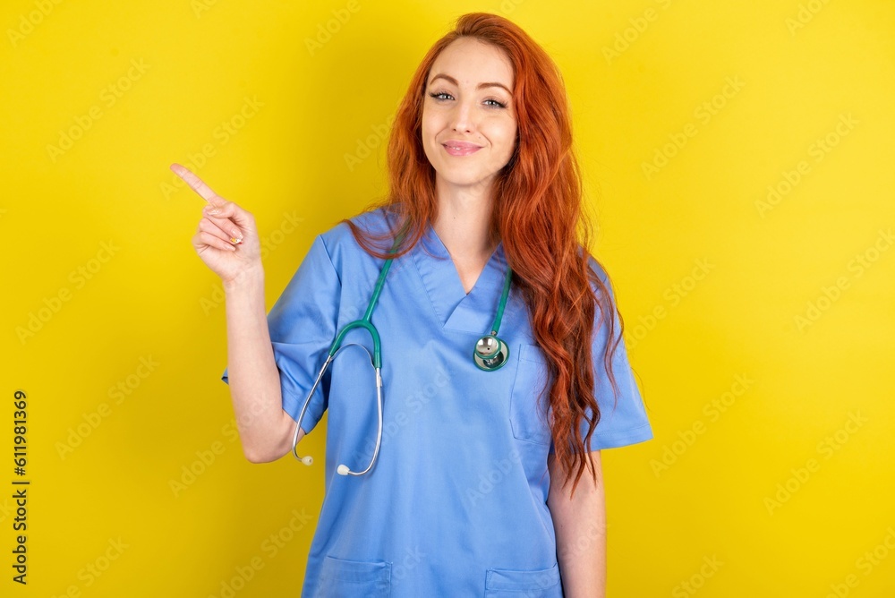 Positive young red-haired doctor woman over yellow studio background with satisfied expression indicates at upper right corner shows good offer suggests to click on link Positive young red-haired doctor woman over yellow studio background with satisfied expression indicates at upper right corner shows good offer suggests to click on link