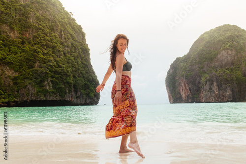 Woman in bikini and sarong enjoying in tropical beach paradise. Having fun summer beach trip in Thailand.