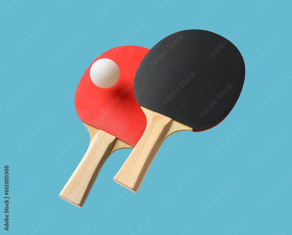 Pair of table tennis paddle and ball isolated on a blue background Pair of table tennis paddle and ball isolated on a blue background