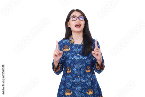 Excited Asian female in batik korpri, indonesian traditional uniform looking and pointing above