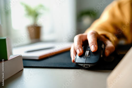 Close up shot of a man's hand in yellow outfits using and clicking a computer mouse on table. copy space