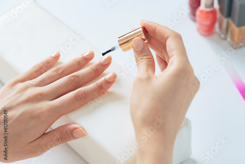 A woman applying nail polish to her nails in her room. Nail care.