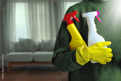 Charwoman standing with a bucket and cleaning products on blurred office background.
