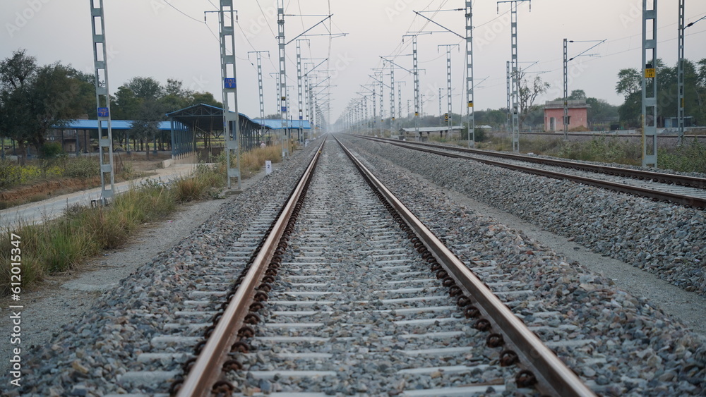 Railroad tracks of the Indian Pacific Railway near Jaipur, India. Single track railway line with electricity pole.