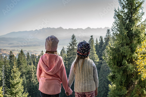 dwójka dzieci trzyma się za ręce patrząc na panoramę Tatr, Gorce, Łapsowa Polana, Polska, Małopolska, małopolskie, Nowy Targ, Tatry