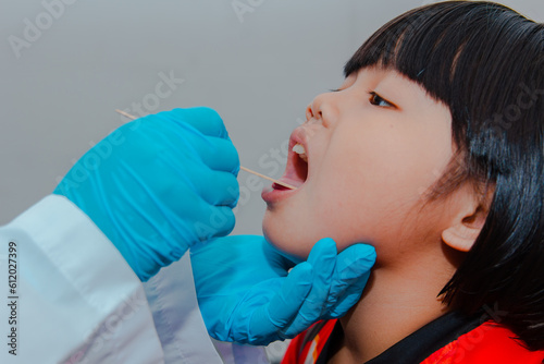 The doctor uses a tongue depressor to examine the child's tongue.