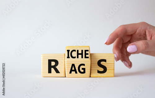 Rags vs Riches symbol. Businessman hand points at wooden cubes with words Rags and Riches. Beautiful white background. Rags vs Riches and business concept. Copy space