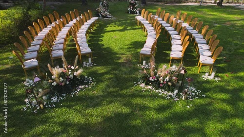 Aerial drone top view of the wedding arch and chairs in garden near beach. Wedding ceremony with a decor on a green lawn. Sunny day summer. Beatiful wedding decorated in summer day. nobody