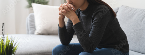 Cuadro en lienzo Unhappy anxiety young Asian woman sitting on the sofa at home.