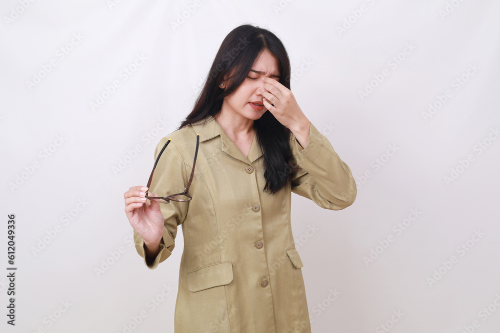 Tired Indonesian civil servant worker holding eyeglasses and suffering from headache
