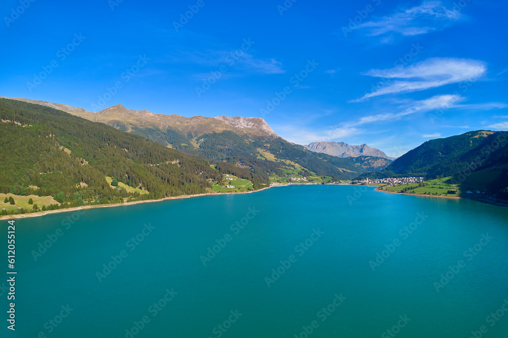 Aerial view of lake (Reschensee). Large reservoir surrounded by mountains at sunny noon. Recreation area for tourists and sportsmen. Italy, Vinschgau, Reschen.