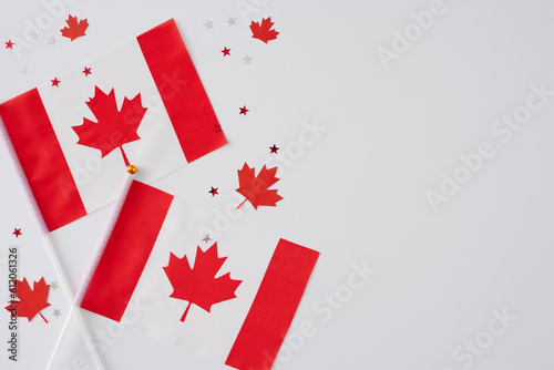 July 1st  Canada Day festivities concept. Top view flat lay of canadian flags, red maple leaves, party confetti on white background with blank space for message or advert