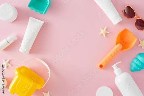 Summer skincare concept for kids. Top view flat lay of cosmetic tubes, beach toys, eyewear, starfish on pastel pink background with blank space for text or ads © Goncharuk film
