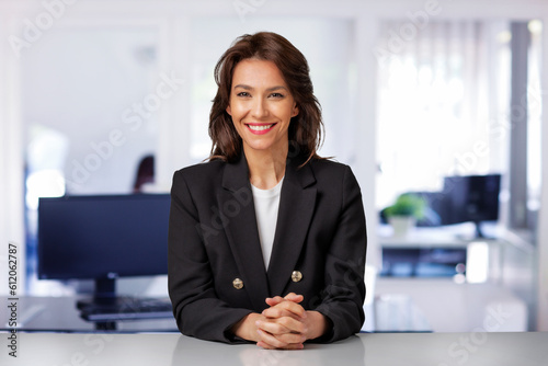 Confident mid aged businesswoman sitting at desk in the office