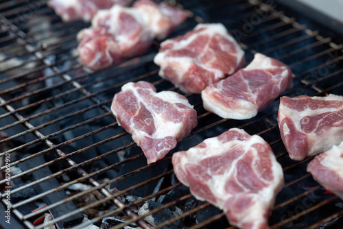 Pieces of pork being prepared on a bbq grill