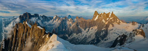 A panoramic view of the peaks and glaciers of the Mont Blanc massif at sunset. The sharp granite peaks  are illuminated by the evening sun. © Natalia