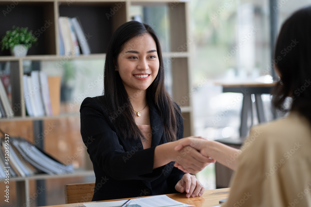 Recruiter shaking hands with a young female candidate after a job interview.
