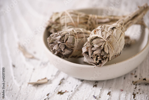 White Sage smudge sticks (Salvia apiana) in a white bowl on an old white wooden table