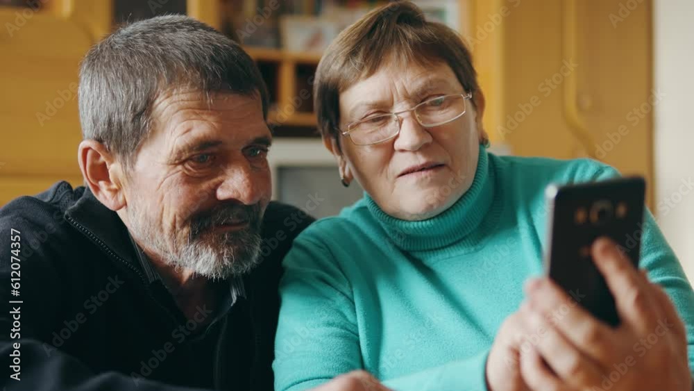 The couple are sitting in the living room watching something on the phone. The couple are sitting in the living room watching something on the phone.