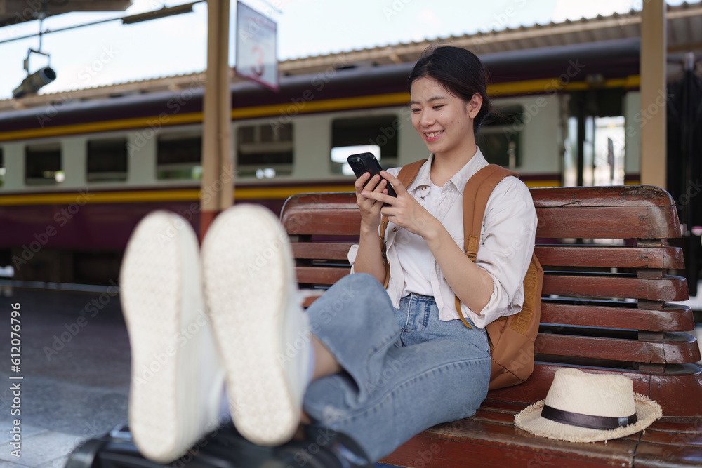 Asian Tourist person backpacker to travel at train station and using mobile phone. Tourism and travel in the summer Asian Tourist person backpacker to travel at train station and using mobile phone. Tourism and travel in the summer