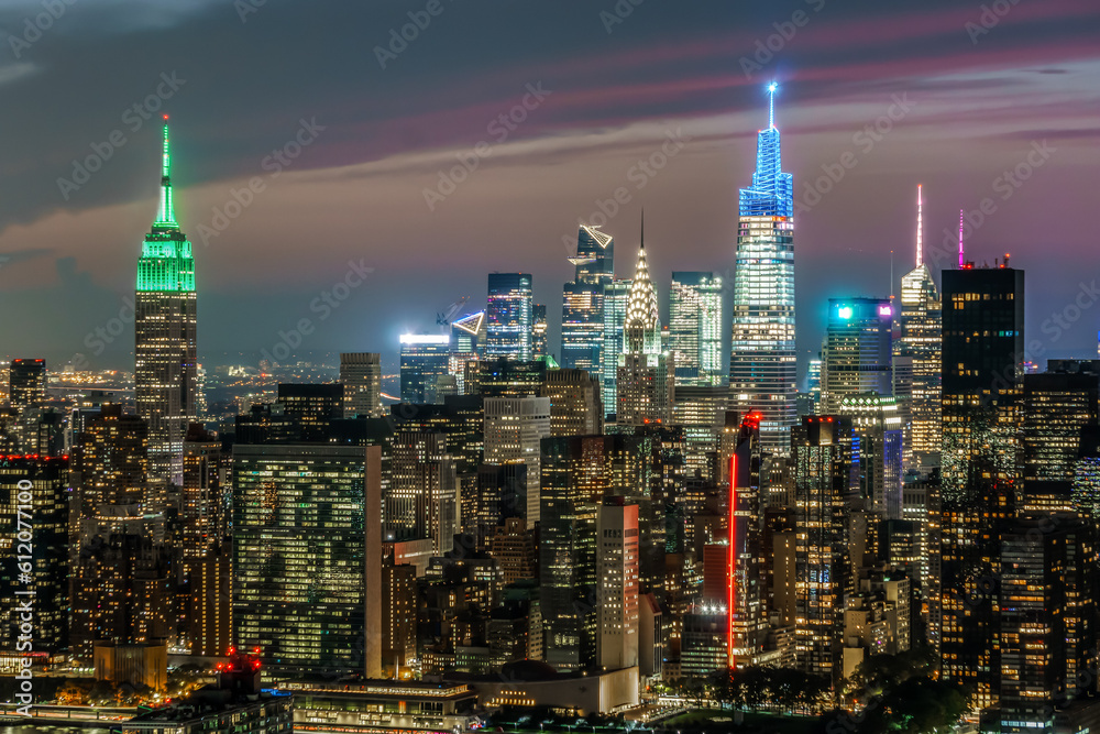 Aerial view of New York City at Night with the Empire State Building lit up in green.
