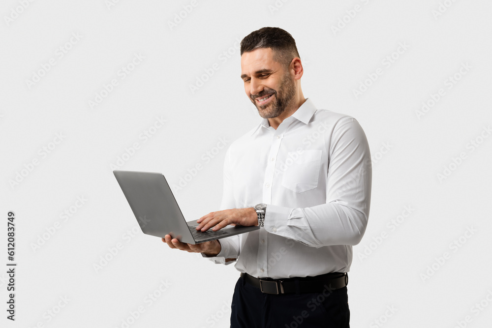 Happy european middle aged businessman typing on computer, chatting in social networks, surfing in internet and smiling Happy european middle aged businessman typing on computer, chatting in social networks, surfing in internet and smiling