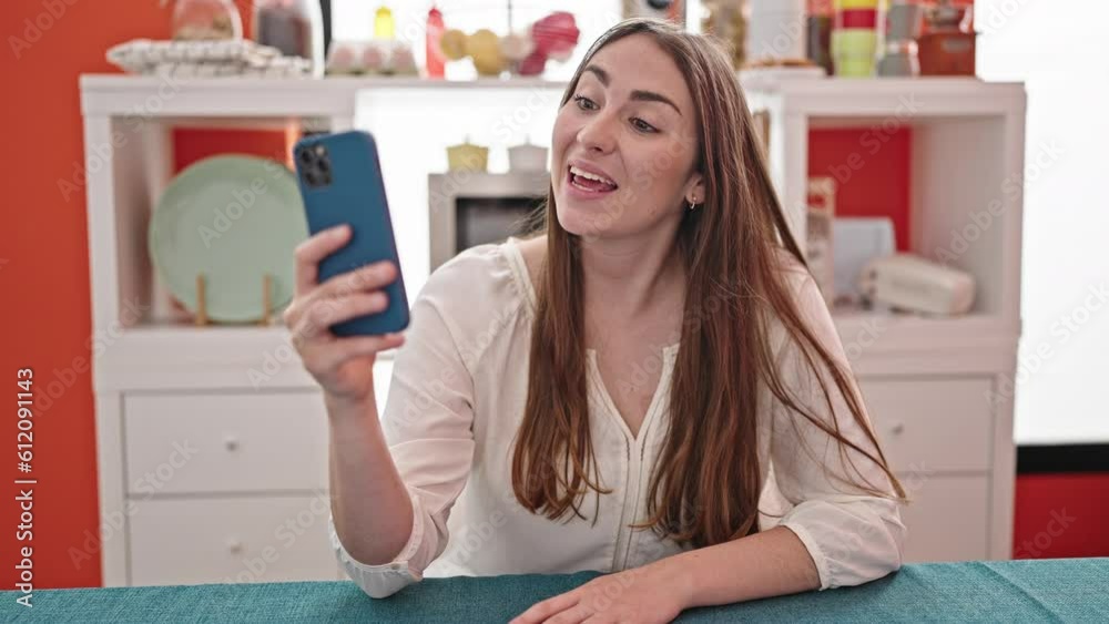 Young beautiful hispanic woman having video call sitting on table at dinning room Young beautiful hispanic woman having video call sitting on table at dinning room