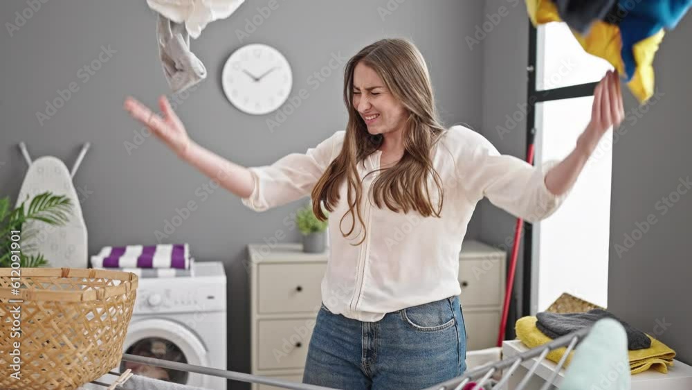 Young beautiful hispanic woman throwing clothes at laundry room