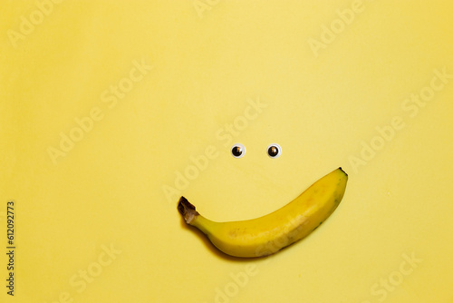 Banner con emoticones de carita sonriente y banana con ojitos. espacio para texto, en fondo amarillo, concepto de dia mas feliz del año, happy yellow day, verano.