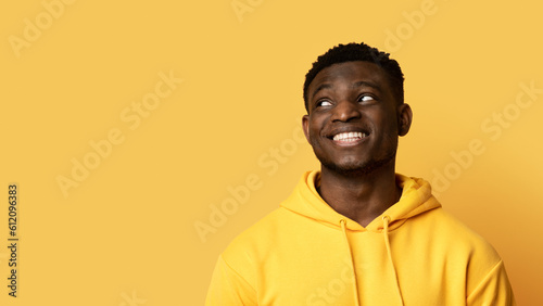 Cool smiling black guy looking at copy space  yellow background