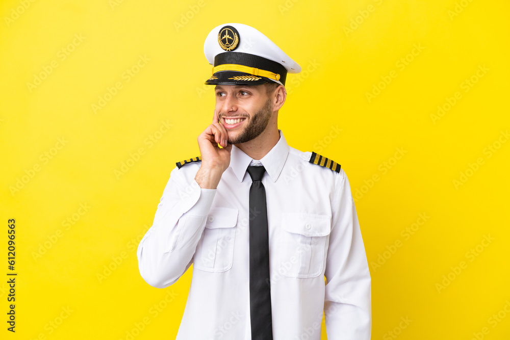 Airplane caucasian pilot isolated on yellow background thinking an idea while looking up