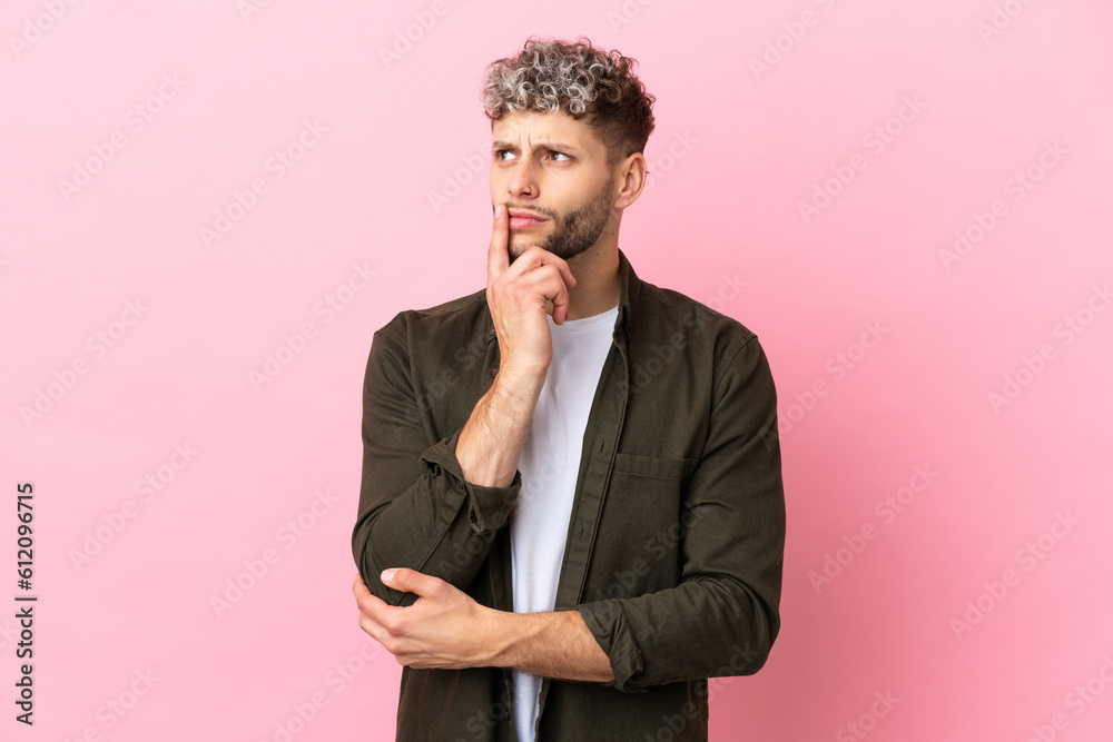 Young handsome caucasian man isolated on pink background having doubts while looking up Young handsome caucasian man isolated on pink background having doubts while looking up