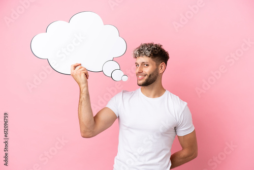 Young handsome caucasian man isolated on pink background holding a thinking speech bubble