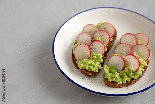Homemade Radish Avocado Toast with Salt and Pepper on a Plate, side view. Copy space.