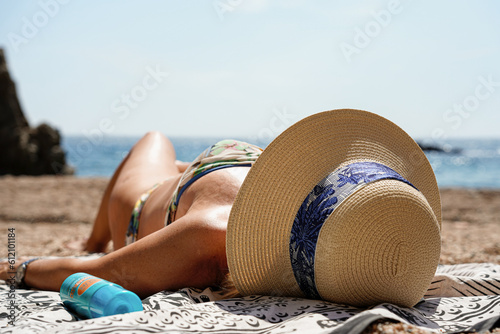 unrecognizable old woman sunbathing lying on the beach with sun protection on summer vacation
