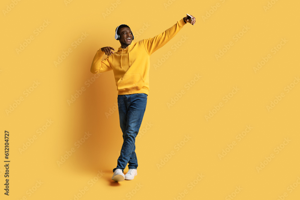 Positive black guy taking selfie on smartphone, using headphones Positive black guy taking selfie on smartphone, using headphones