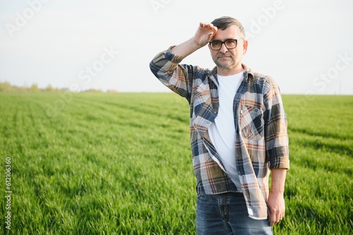 Portrait of senior farmer standing in green wheat field. © Serhii