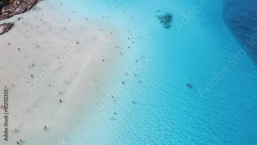 Aerial view of famous La Pelosa beach at sunny summer day. Stintino, Sardinia island, Italy. Top view of white sandy beach, umbrella, swimming people, transparent blue sea. Tropical seascape