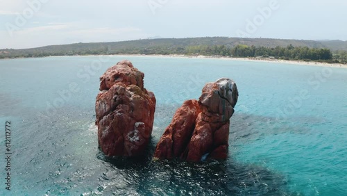 Aerial view of red cliffs in the sea at sunset in summer. Top drone view of rocks, transparent blue water, empty sandy beach in Sardinia island, Italy. Tropical. Exotic place. Nature