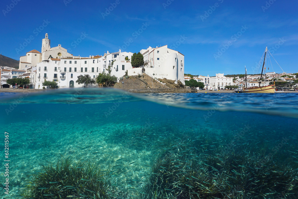Spain, Cadaques, touristic coastal village on the shore of the Mediterranean sea with seagrass and fish underwater, split view over and under water surface, Costa Brava, Catalonia