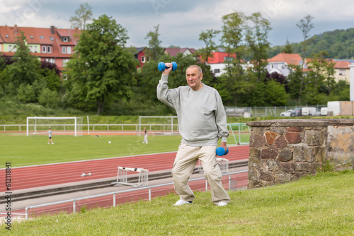 An elderly man goes in for sports on the background of the stadium on a summer evening