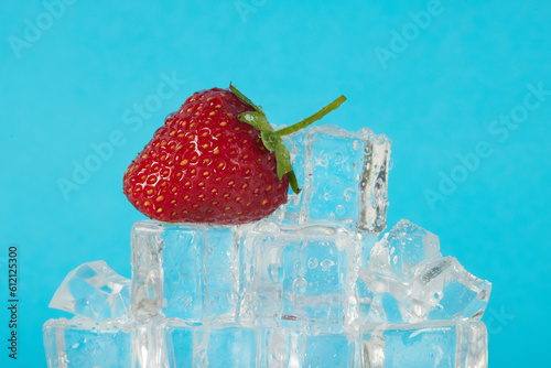 ripe strawberries lie on ice cubes on a blue background