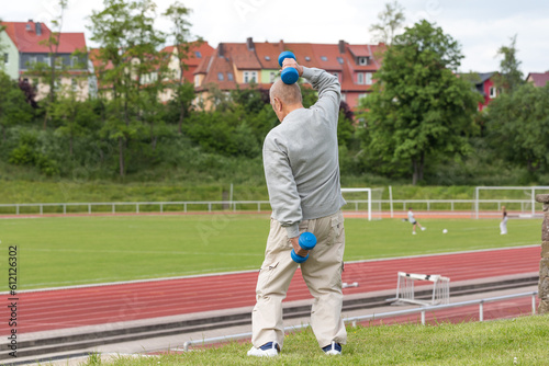 Sports in oldAn elderly man goes in for sports on the background of the stadium on a summer eveningage