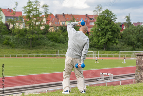 Sports in oldAn elderly man goes in for sports on the background of the stadium on a summer eveningage